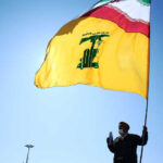 An Iranian carries the Iranian and Hezbollah flags during the commemoration of the 41st anniversary of the Islamic revolution in Tehran