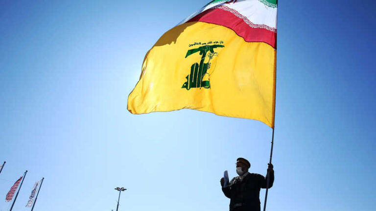 An Iranian carries the Iranian and Hezbollah flags during the commemoration of the 41st anniversary of the Islamic revolution in Tehran